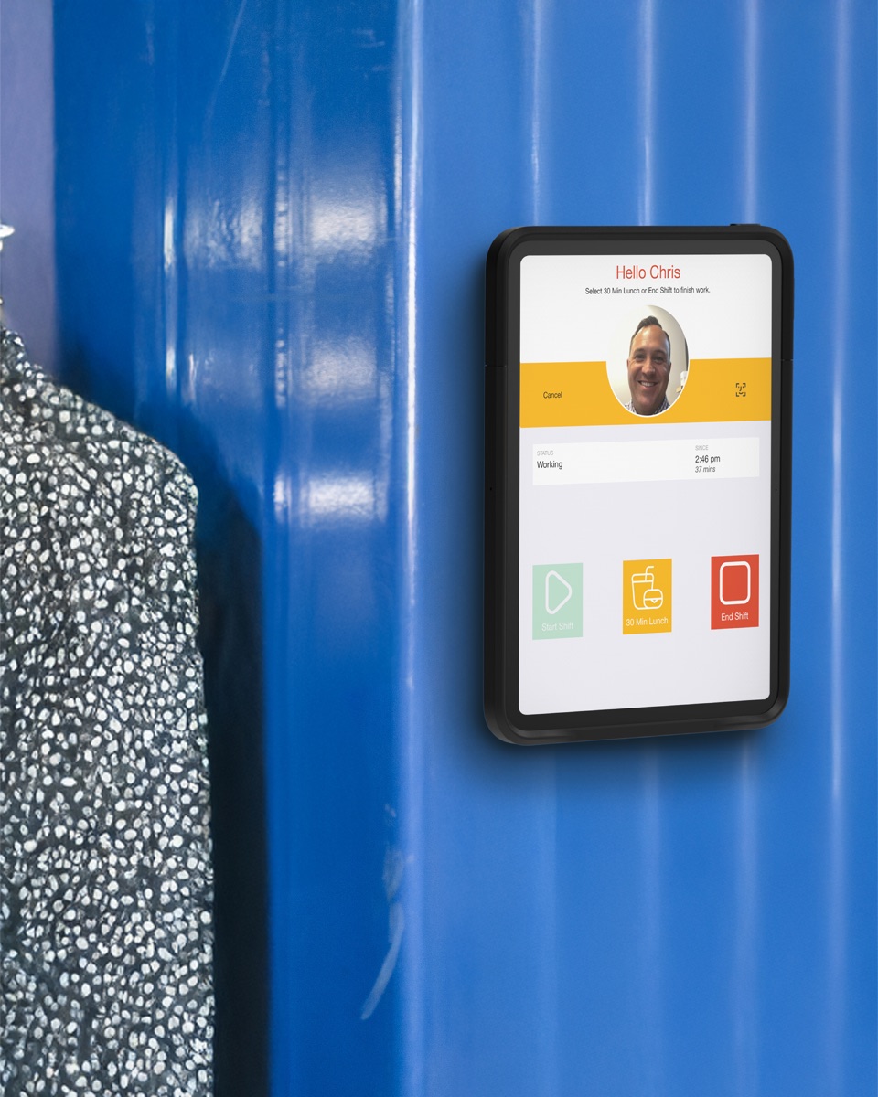 A wall-mounted iPad in the back of house of a store, running the NoahFace clock-in screen