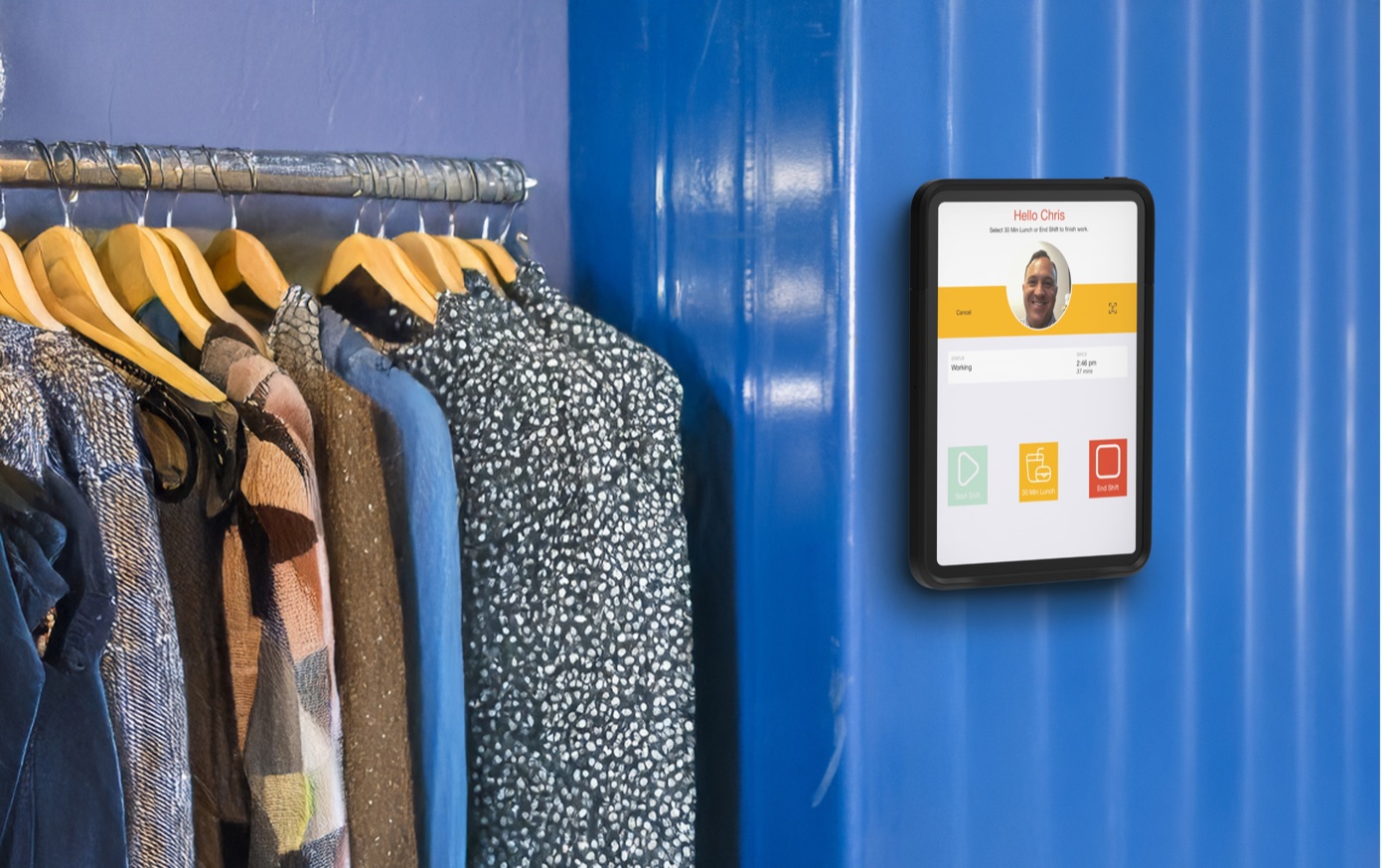 A wall-mounted iPad in an IPORT case showing the NoahFace clock-in screen in a stockroom